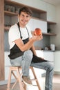 Attractive man with an apple sitting in a home kitchen Royalty Free Stock Photo