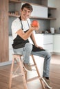 attractive man with an apple sitting in a home kitchen Royalty Free Stock Photo