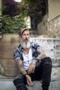 Attractive man with a beard and tattoos is sitting on the stairways in the old city of athens