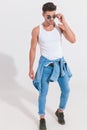 Attractive man with denim shirt around waist fixes sunglasses Royalty Free Stock Photo