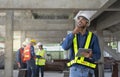 attractive man engineer wear hardhat and vest holding tablet working at the building under construction Royalty Free Stock Photo