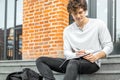 Attractive man holding notepad in his hands and sitting on concrete steps. Royalty Free Stock Photo
