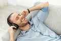 Attractive man listening music lying on the couch and listening to music on headphones Royalty Free Stock Photo