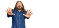 Attractive man with long hair and beard wearing casual clothes afraid and terrified with fear expression stop gesture with hands, Royalty Free Stock Photo
