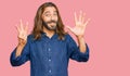 Attractive man with long hair and beard wearing casual clothes showing and pointing up with fingers number eight while smiling Royalty Free Stock Photo