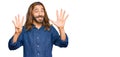 Attractive man with long hair and beard wearing casual clothes showing and pointing up with fingers number nine while smiling Royalty Free Stock Photo
