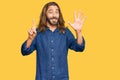 Attractive man with long hair and beard wearing casual clothes showing and pointing up with fingers number six while smiling Royalty Free Stock Photo