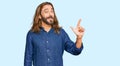 Attractive man with long hair and beard wearing casual clothes showing and pointing up with fingers number two while smiling Royalty Free Stock Photo