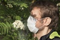 Attractive man with medical mask on his face, shadow in his eyes against pollen cloud