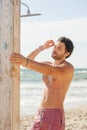 Attractive man with muscular body taking shower on the sea beach Royalty Free Stock Photo