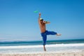 Attractive man playing frisby on beach in summer