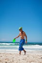 Attractive man playing frisby on beach in summer