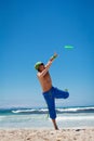 Attractive man playing frisby on beach in summer