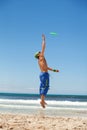 Attractive man playing frisby on beach in summer