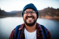 An attractive man pulls a silly grin on a hiking trip by a lake