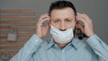 Attractive man puts on surgical mask on his face. Cold, flu, virus, acute respiratory infections, quarantine, epidemic, irony, Royalty Free Stock Photo