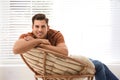 Attractive man relaxing in papasan chair near window Royalty Free Stock Photo