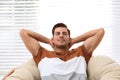 Attractive man relaxing in papasan chair near window Royalty Free Stock Photo