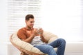 Attractive man relaxing in papasan chair near window Royalty Free Stock Photo