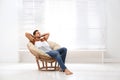 Attractive man relaxing in papasan chair near window. Space for text Royalty Free Stock Photo