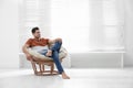 Attractive man relaxing in papasan chair near window at home Royalty Free Stock Photo