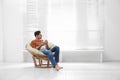 Attractive man relaxing in papasan chair near window. Space for text Royalty Free Stock Photo