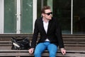 An attractive man sitting down outside wearing jeans and a blazer Royalty Free Stock Photo