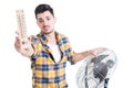Attractive man with thermometer use electric fan to cool down Royalty Free Stock Photo