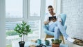 Attractive man using digital tablet sitting in chair at balcony in loft modern apartment Royalty Free Stock Photo