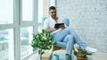 Attractive man using digital tablet sitting in chair at balcony in loft modern apartment Royalty Free Stock Photo