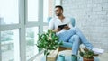 Attractive man using digital tablet sitting in chair at balcony in loft modern apartment Royalty Free Stock Photo