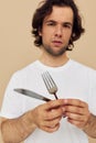 Attractive man in a white T-shirt with knife with fork isolated background Royalty Free Stock Photo