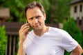 Attractive man in white t-shirt talking on mobile phone, Businessman outdoors Royalty Free Stock Photo