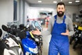 Attractive man worker displaying various motorcycles in workshop Royalty Free Stock Photo