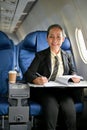 An attractive mature Asian businesswoman working on her business report during the flight Royalty Free Stock Photo