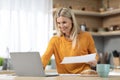 Attractive mature blonde woman freelancer working from home, reading documents Royalty Free Stock Photo