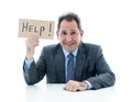 Attractive mature businessman overwhelmed and tired holding a help sign Royalty Free Stock Photo