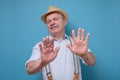Attractive mature man in summer hat showing refusal gesture Royalty Free Stock Photo