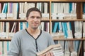 Attractive mature student standing in a library holding some books Royalty Free Stock Photo