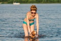 Attractive mature woman enjoying playing with her dog in whater during summer. Summer time and lifestyle. Dachshund swims in the Royalty Free Stock Photo