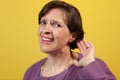 Attractive mature woman in purple blouse with hand to ear