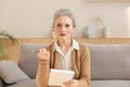 Attractive mature woman sitting on the couch and making notes in diary Royalty Free Stock Photo