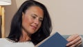 Attractive mature woman smiling joyfully reading interesting book Royalty Free Stock Photo