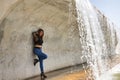 Attractive mature woman, with transparent black shirt, jeans and heels, posing next to a waterfall in a sensual and provocative