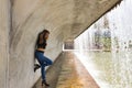 Attractive mature woman, with transparent black shirt, jeans and heels, posing next to a waterfall in a sensual and provocative