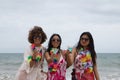 Attractive mature woman with two young, pretty, brunette South American women in bikinis, sunglasses and flower necklaces toasting Royalty Free Stock Photo