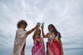 Attractive mature woman with two young, pretty, brunette South American women in bikinis, sunglasses and flower necklaces toasting Royalty Free Stock Photo
