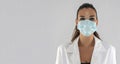 Attractive female doctor with virus protection mask looking straight ahead and white background