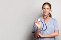 Attractive mid adult doctor woman medical worker or nurse holding stethoscope on grey background Royalty Free Stock Photo