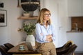 Attractive mid aged woman deep in thought and standing in a modern home Royalty Free Stock Photo